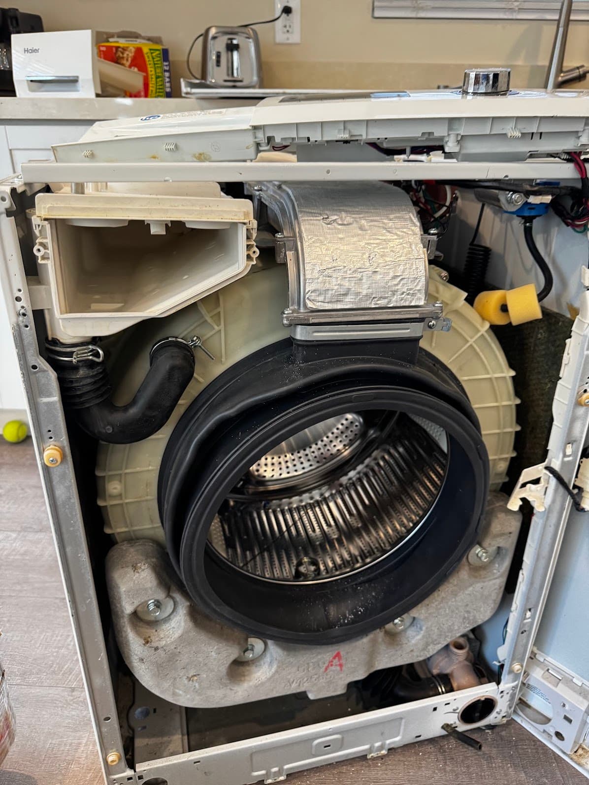 Front-load washer fully disassembled showing drum and hoses